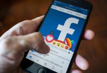 Hand using smartphone with Facebook reactions on screen
