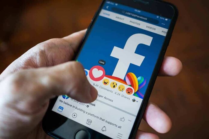 Hand using smartphone with Facebook reactions on screen