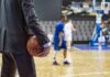 WNBA Definition Gap Explodes Basketball coach in suit holding ball courtside