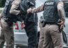 Police officers arresting a person beside a car