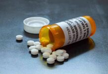 Prescription pill bottle with white tablets spilled on a surface