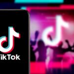 Smartphone showing TikTok logo against neon party silhouettes