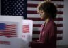 Voter at a polling booth with an American flag backdrop