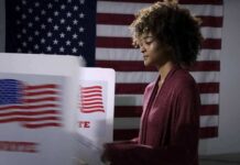 Voter at a polling booth with an American flag backdrop