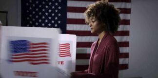 Voter at a polling booth with an American flag backdrop
