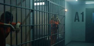 prison cell with inmates in orange jumpsuits behind bars