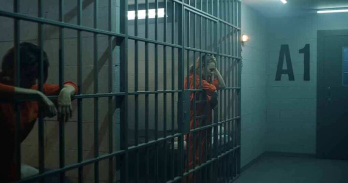 prison cell with inmates in orange jumpsuits behind bars