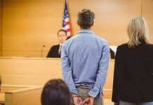Defendant in handcuffs stands before a judge in a courtroom