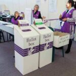 Election workers near ballot boxes in a polling station