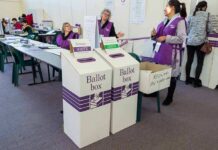 Election workers near ballot boxes in a polling station