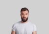 Man with beard making surprised face against gray background