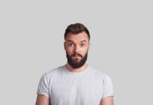Man with beard making surprised face against gray background