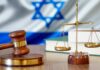 Gavel and scales of justice with Israeli flag in background