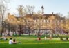 Students relaxing on a campus quad in front of a brick academic building
