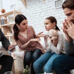 Family and counselor in tense discussion with upset child holding teddy bear