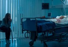 hospital room with child in bed and adult sitting nearby