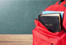 Red backpack with books on a classroom desk