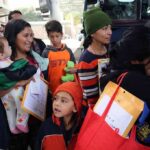 Group of people with children waiting in line near a bus