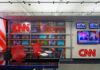 CNN newsroom set with red chairs and multiple TVs