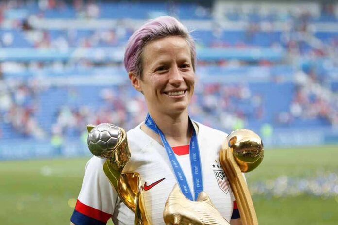 Megan Rapinoe holding soccer trophies on a stadium field