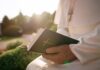 Person in white robe holding a Bible outdoors