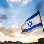 Israeli flag waving against a sunset backdrop with clouds