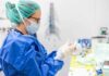 medical professional in blue gown putting on sterile gloves