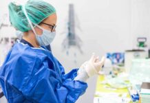 medical professional in blue gown putting on sterile gloves