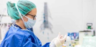 medical professional in blue gown putting on sterile gloves