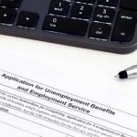 Unemployment benefits application form with keyboard and pen