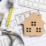 House model on architectural blueprints with tools and keyboard