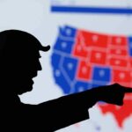 silhouetted person pointing in front of a U.S. election map