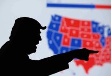 silhouetted person pointing in front of a U.S. election map