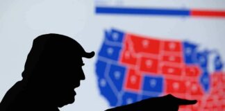 silhouetted person pointing in front of a U.S. election map