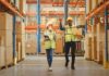 Warehouse workers walking among shelves with boxes
