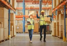 Warehouse workers walking among shelves with boxes