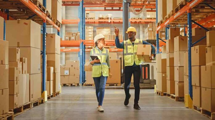 Warehouse workers walking among shelves with boxes