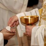 Priest gives communion wafer to a congregant