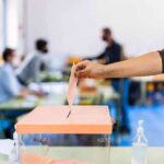 Hand casting ballot into a box at a polling station