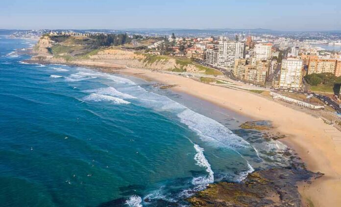 Aerial view of a coastal city beach with waves and rocky shoreline