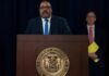 Man speaks at podium with New York County District Attorney seal