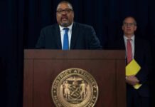 Man speaks at podium with New York County District Attorney seal