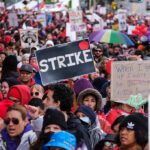 Chuck Howley and Christian Jones in a large protest crowd holding strike signs