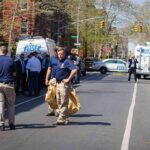 Police officers and investigators at a blocked city street scene