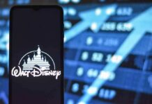 Walt Disney logo on smartphone with stock market chart background