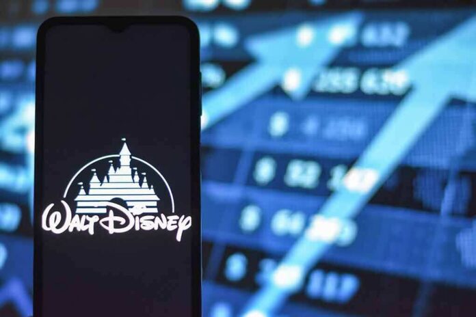 Walt Disney logo on smartphone with stock market chart background
