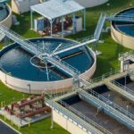 Hochul Freezes AI — Who Pays Now? Wastewater treatment plant with circular clarifiers and aeration tanks