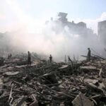 People walking through smoke-filled urban rubble