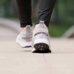 Close-up of person walking in gray sneakers