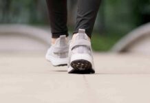 Close-up of person walking in gray sneakers